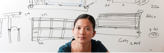 Woman in front of a whiteboard with dimensions written on it